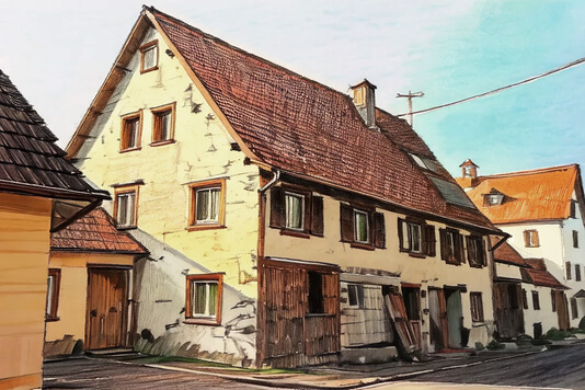 Auf dem Bild ist ein altes, mehrstöckiges Haus mit einem steilen Dach und mehreren Fenstern zu sehen, das an einer ruhigen Straße steht.